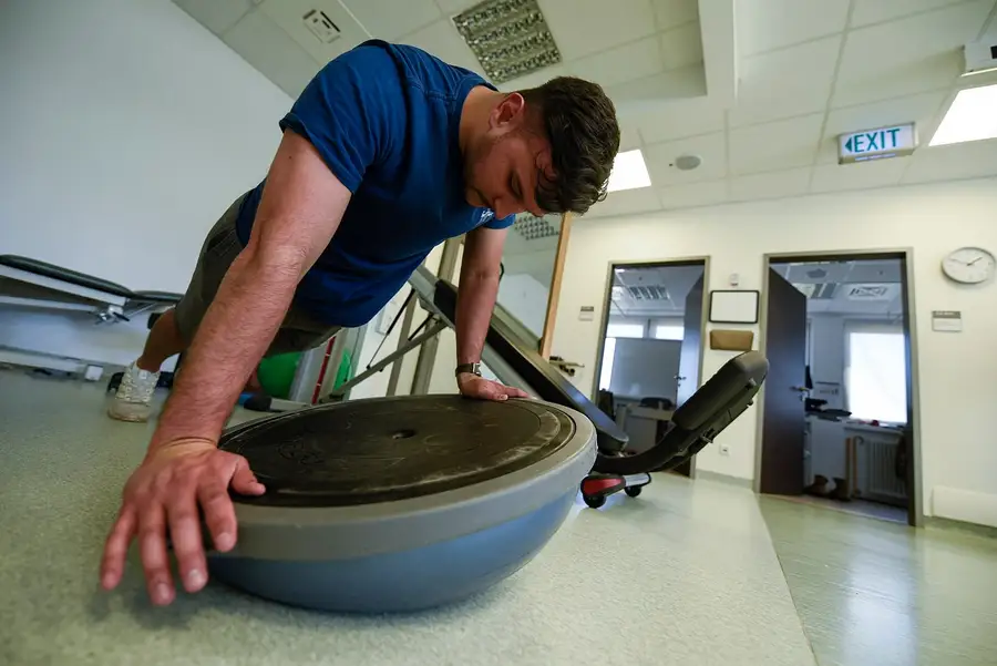 Ćwiczenie stabilizacyjne w podporze na półkuli sensorycznej, wykonywane w sali rehabilitacyjnej.